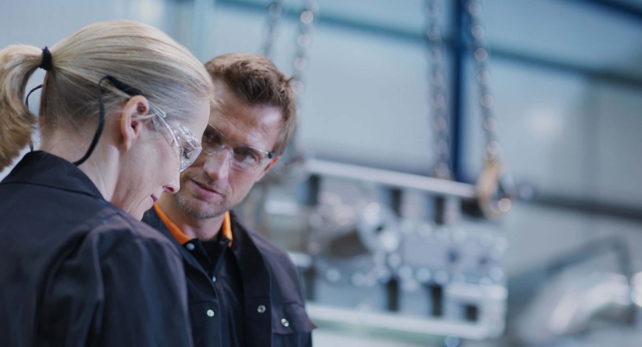 Two people in a factory wearing security glasses