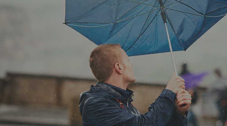 Man holding an umbrella that has turned inside out in the wind